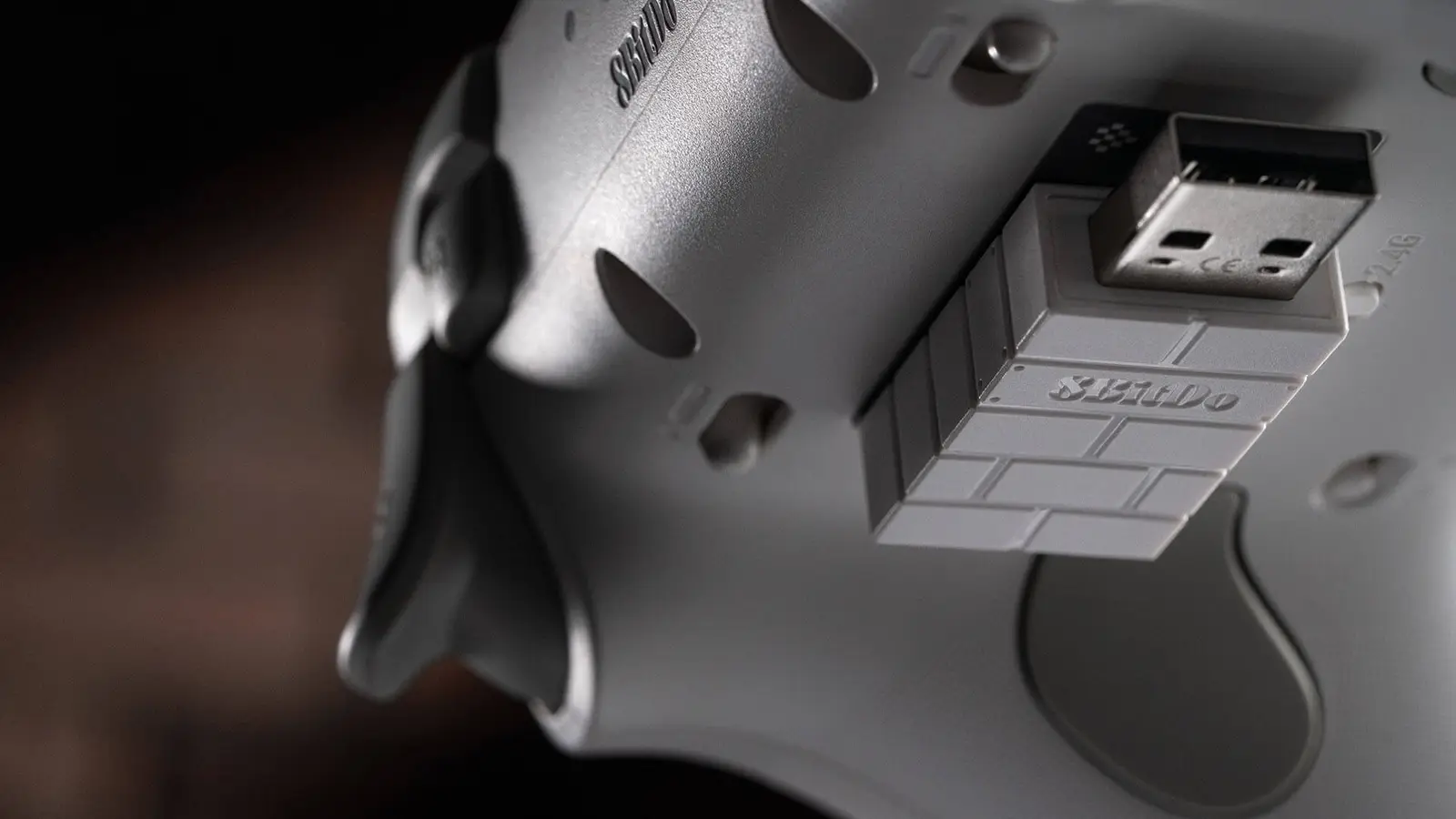 The back of a white Ultimate 3C+ controller with its 2.4GHz USB adapter stuck to the shell, and one of the two back buttons visible below it.