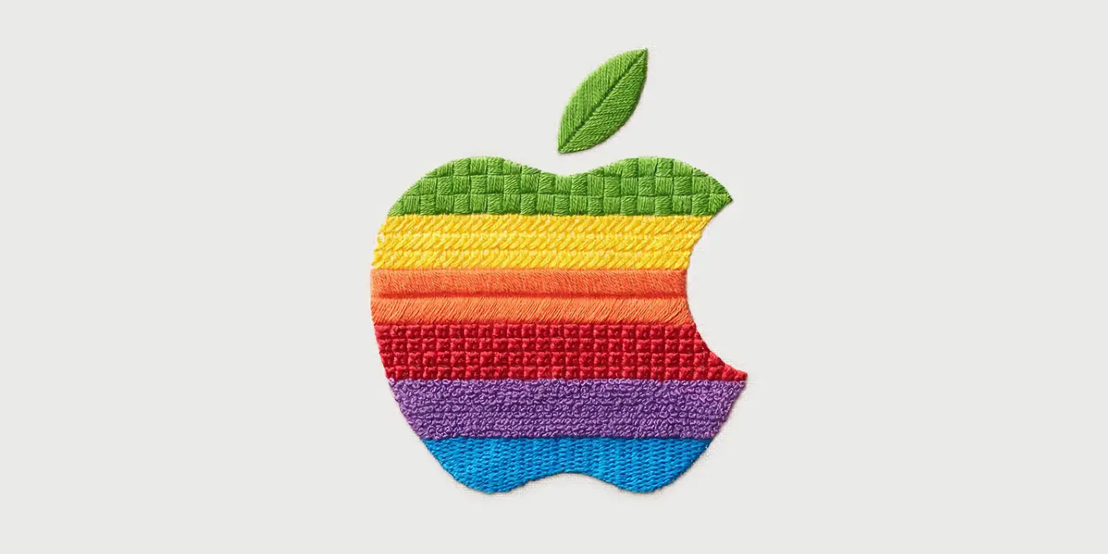 Embroidered rainbow-striped Apple logo on a light background, the artwork of Apple's "Welcome home" invite.