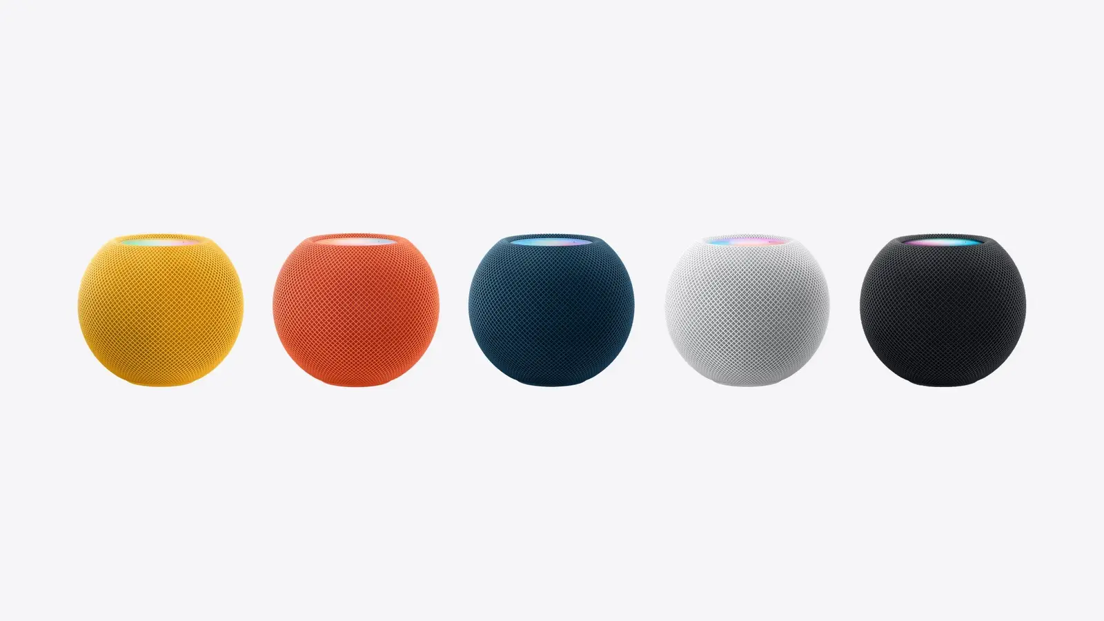 Five HomePod mini speakers in yellow, orange, blue, white and space gray in a row on a light background.