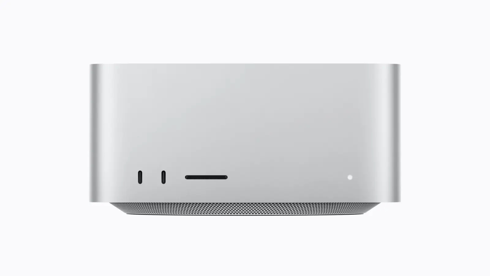 Front of a silver Apple Mac Studio on a plain light background, showing two USB-C ports, an SD card slot and a status light above its perforated base.
