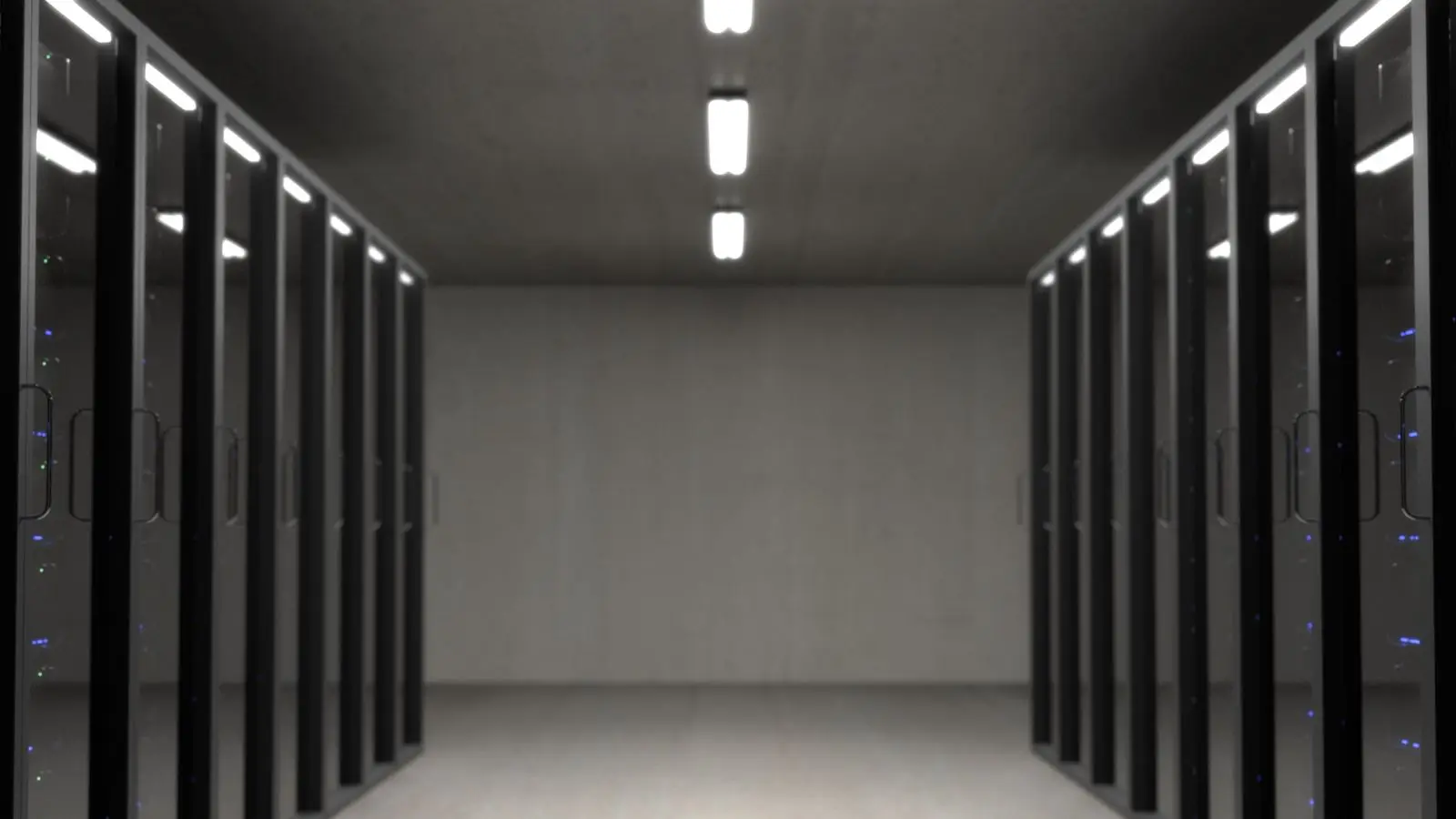 Rows of dark server racks along a data center aisle, with a monitor on a wheeled cart beside them.