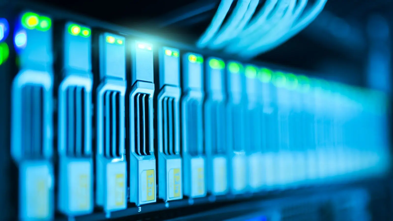 Close-up of server drive bays with glowing blue and green status lights in a rack.