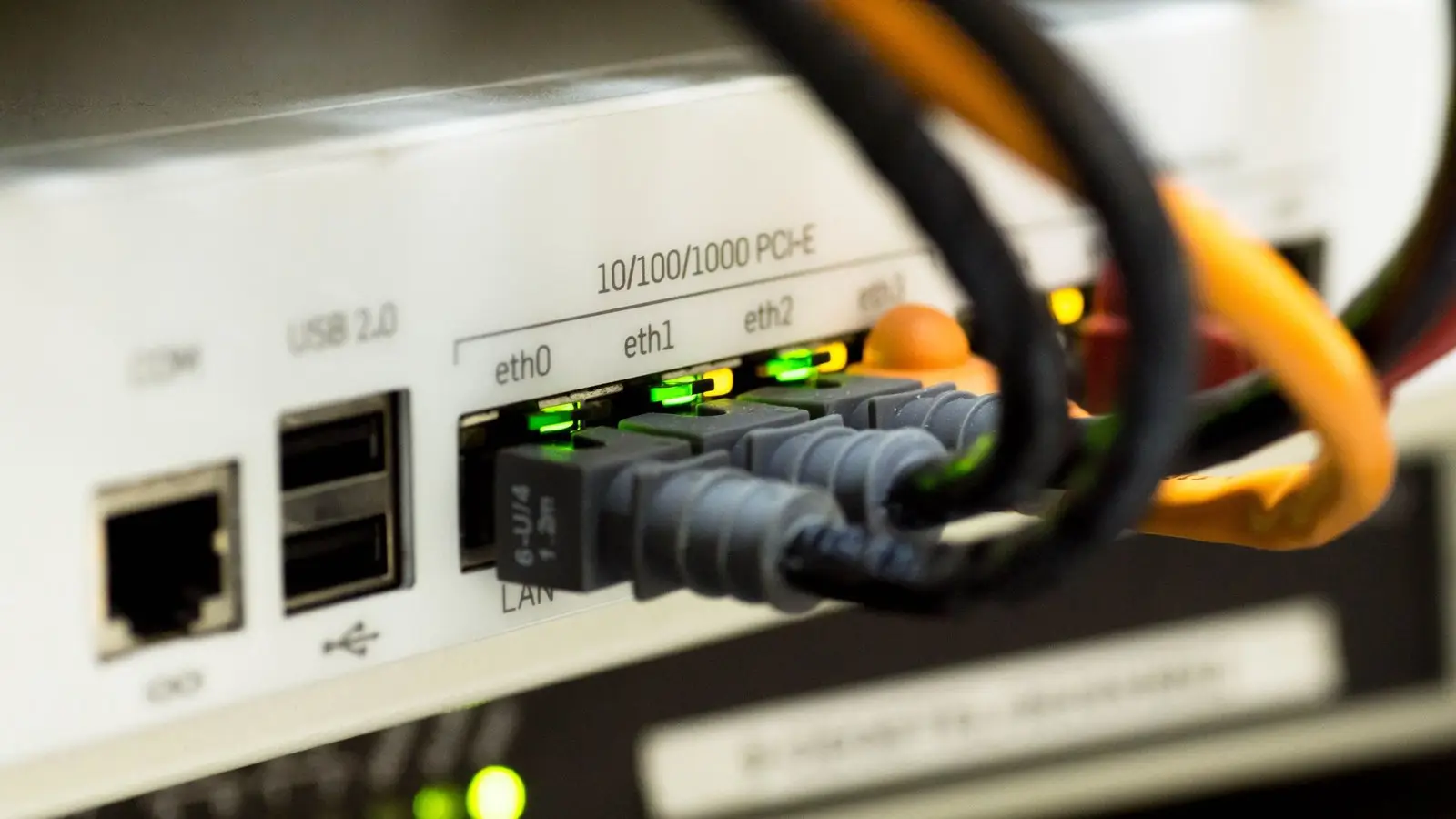 Network cables plugged into ethernet ports on a white device, with green lights lit.