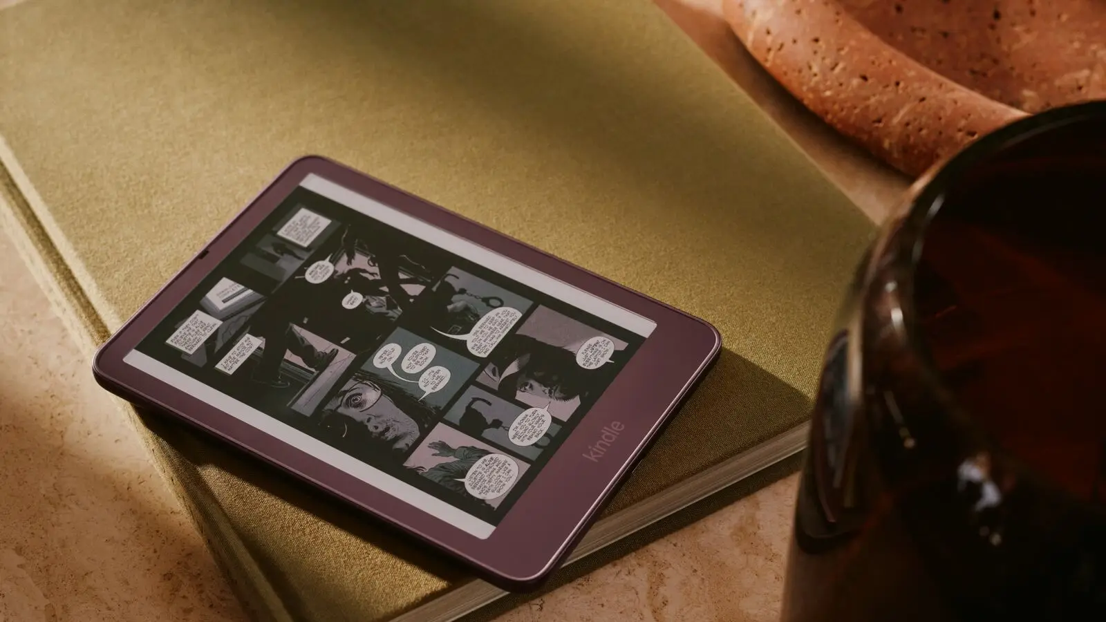 A Kindle e-reader showing a comic page, lying on a book.