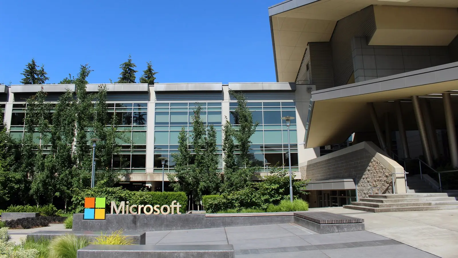 The Microsoft logo and sign in front of a glass-and-concrete office building on the company's Redmond campus.