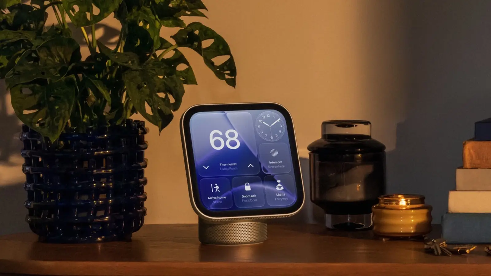 Apple HomeView on a wooden sideboard showing thermostat, clock, intercom, lock and light controls, beside a plant and a candle.