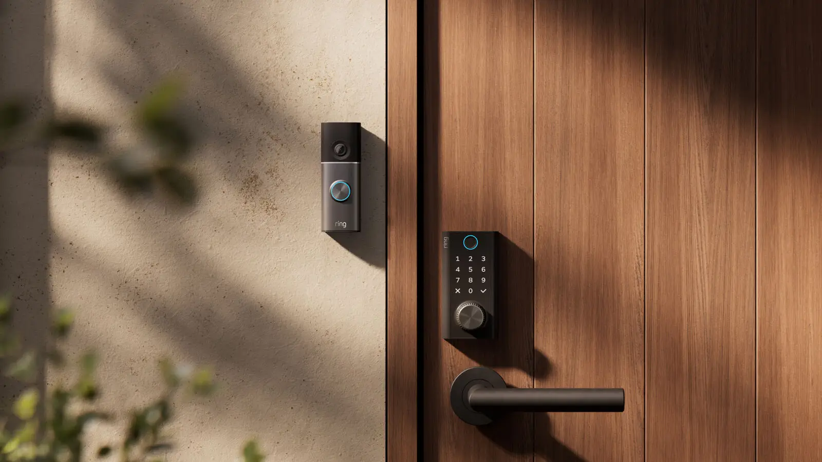 Ring Smart Lock with keypad and dial on a wooden door, with a Ring doorbell on the wall beside it.