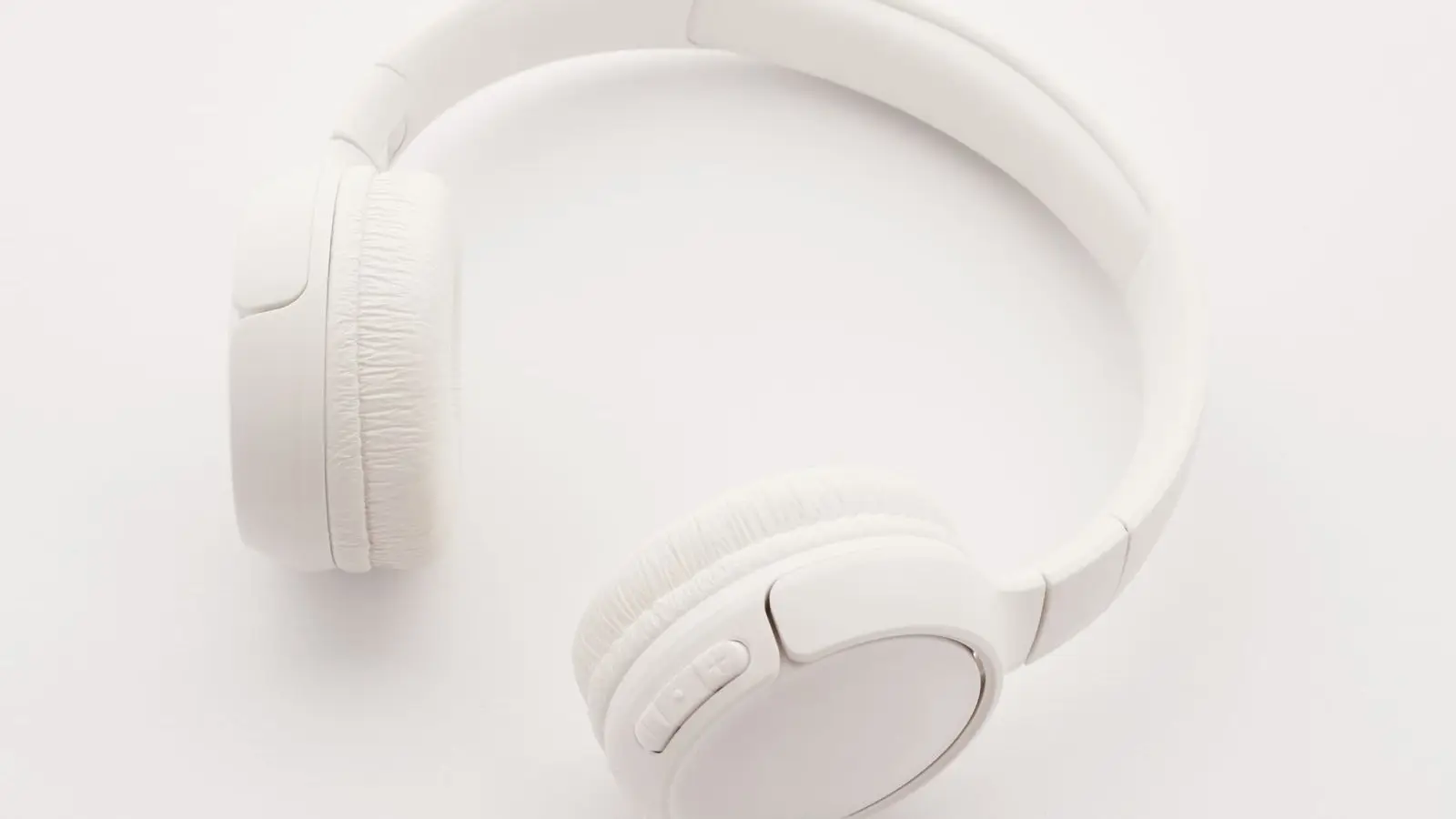 White wireless headphones lying on a plain white background.