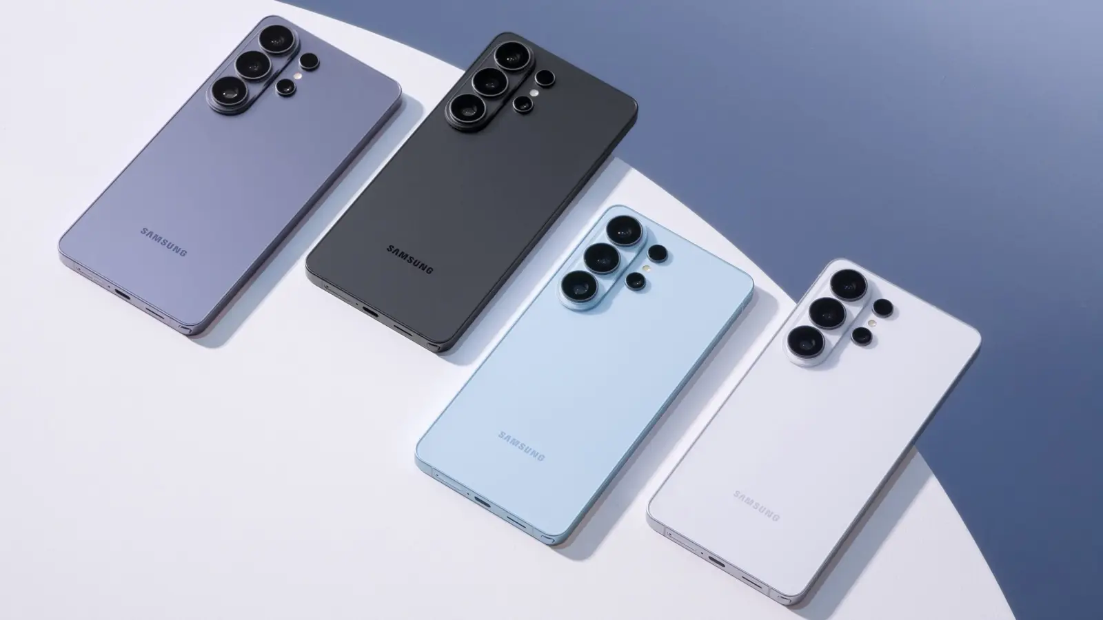 Four Samsung Galaxy S26 phones lying back-up on a white and blue surface.
