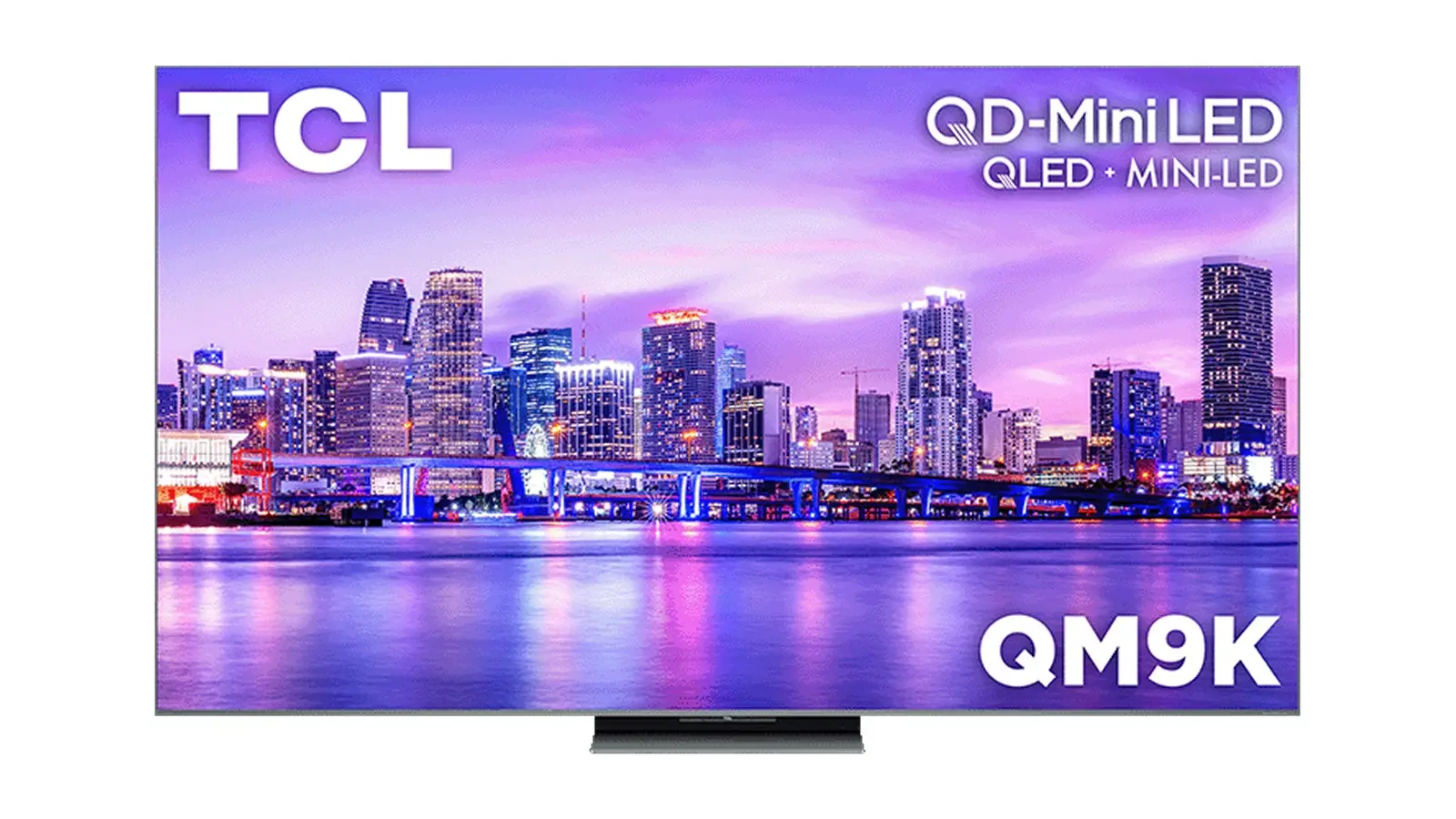 A TCL QM9K television seen from the front, showing a purple dusk skyline with the TCL and QD-Mini LED logos, on a white background.