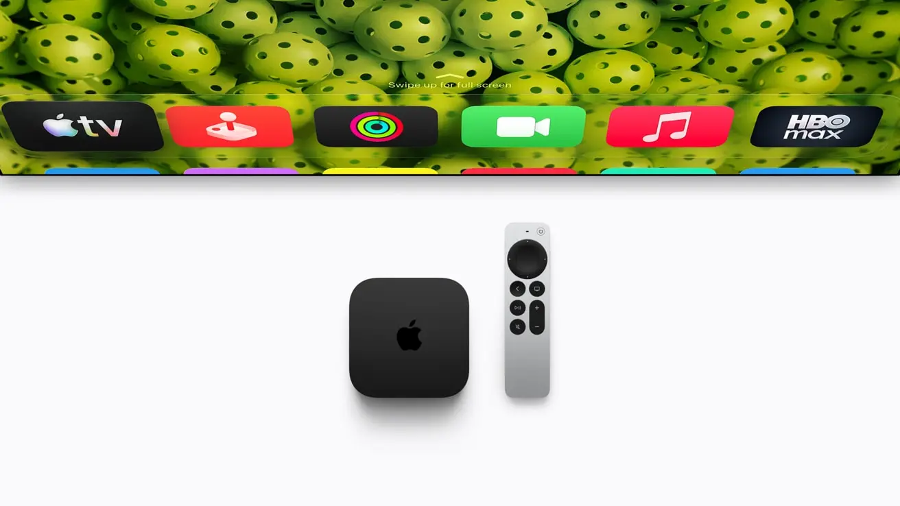 An Apple TV 4K box and Siri Remote on a plain surface below a TV showing the Apple TV home screen